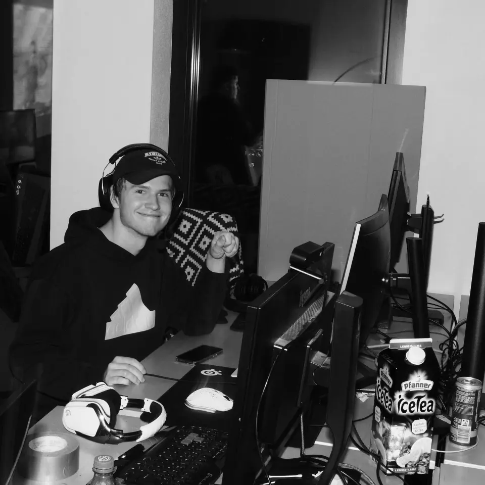 Spieler mit Kappe und Headset an seinem Platz zwischen Monitoren